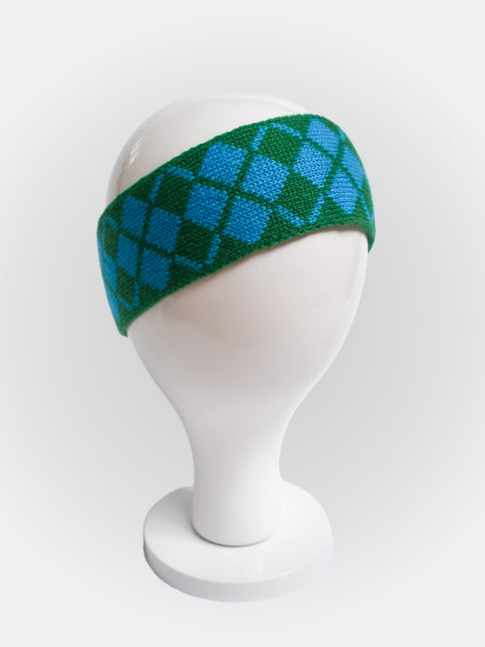 A headband with a bold argyle-inspired pattern in blue and green colors displayed on a mannequin head.