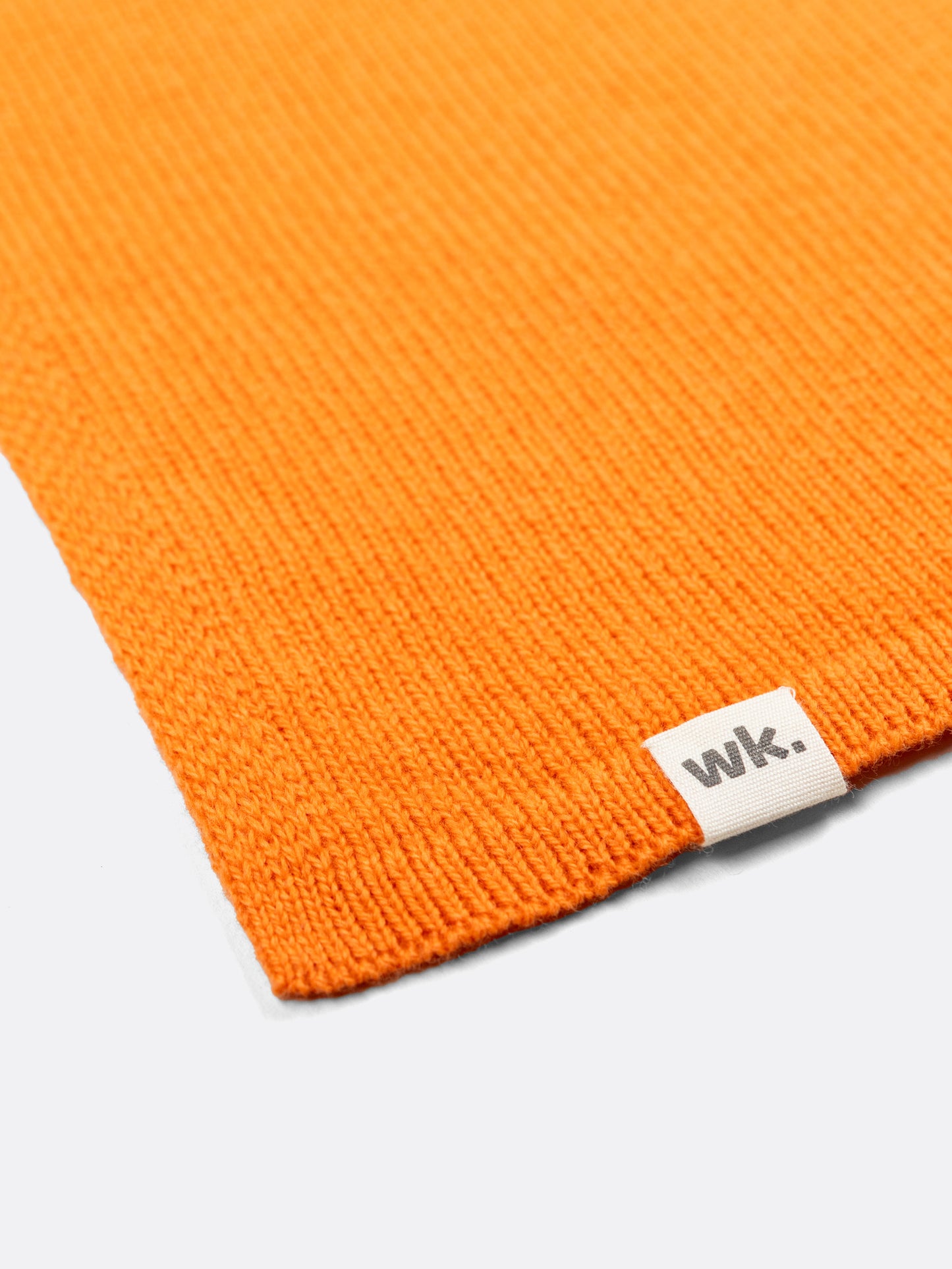 a swatch of plain single jersey knitting made from fine merino wool in an orange colour