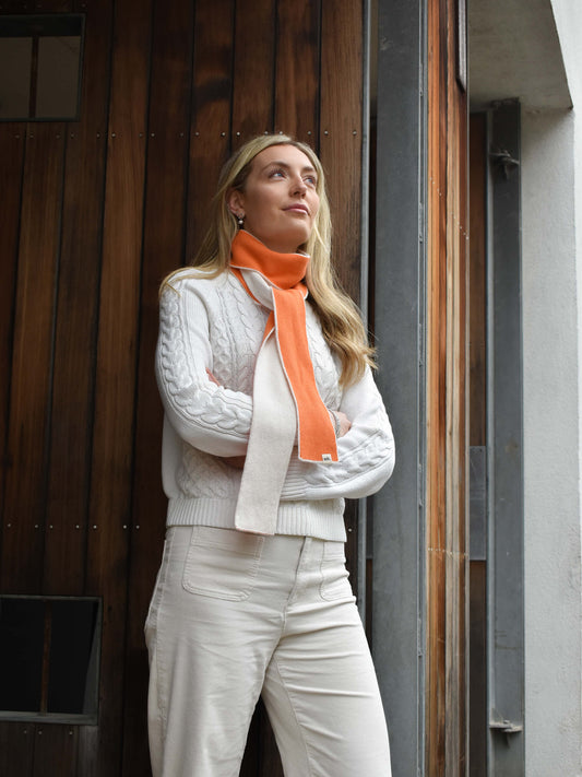 White woman wearing an orange and cream skinny colour block merino wool scarf - Woolkind